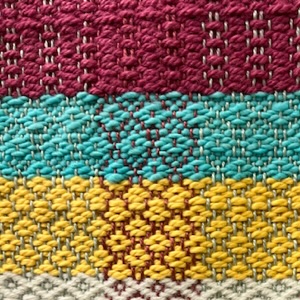 A close-up of the brightly colored weaving done on a floor loom