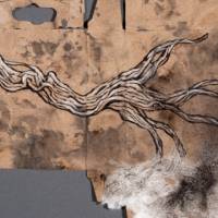 An ink drawing of a piece of driftwood drawn on the flattened brown backside of a Crayola crayon box. There is white tissue paper on the bottom right corner of the piece, evoking seafoam